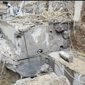Betonsägen und Kernbohrung in Baugrube, freigelegter Betonblock mit Kabeln