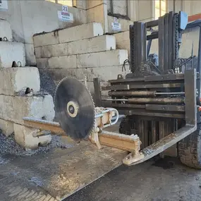 Gabelstapler mit Kreissäge schneidet Betonblöcke in Recyclinghalle