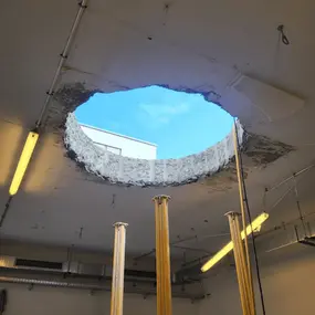 Großes Loch in Betondecke einer Werkstatt, Blick zum Himmel, Bauschaden
