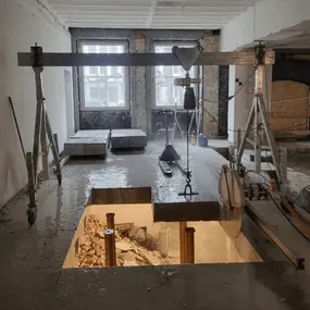 Baustelle Innenausbau: Deckenöffnung mit Schutt und Stahlträger mit Kranhaken
