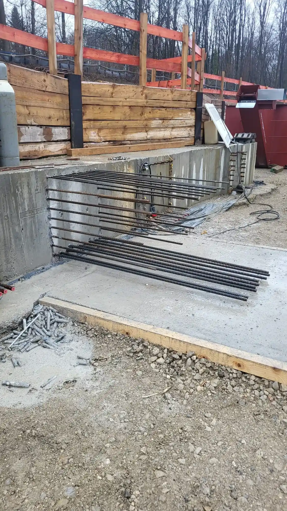 Baustelle mit Betonwand, herausragender Bewehrung und Holzschalung am Hang