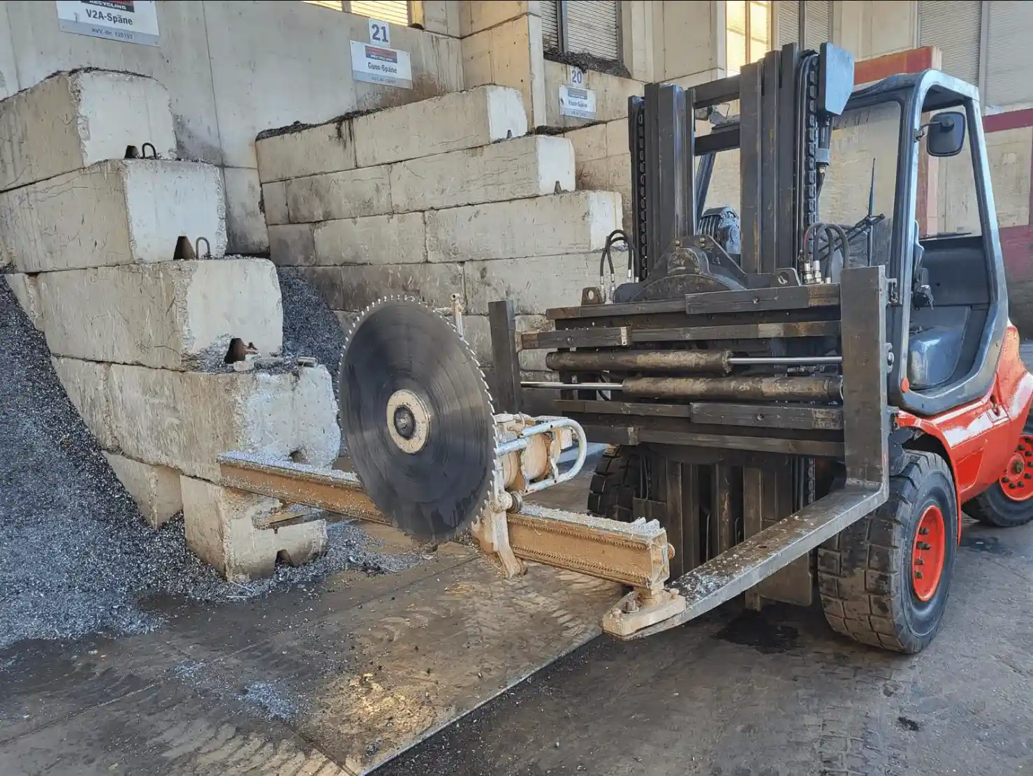 Gabelstapler mit Kreissäge sägt Betonblock in Recyclinghalle, Schotterhaufen